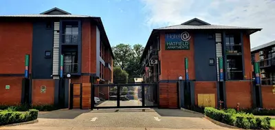 a red brick building with a revolving door at Hotel AT Hatfield Apartments in Pretoria