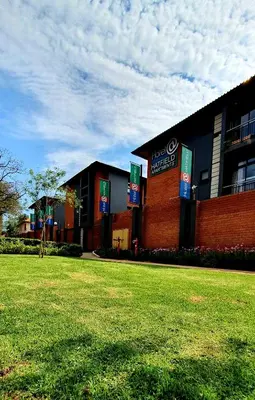a building with a grass field in front of it at Hotel AT Hatfield Apartments in Pretoria
