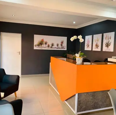 an orange reception desk in a office with black walls at Hotel AT Hatfield Apartments in Pretoria