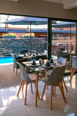 a dining room with tables and chairs and a pool at Hotel AT Hatfield Apartments in Pretoria