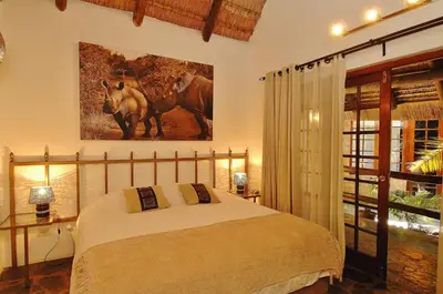 a bedroom with a bed and a painting on the wall at Kaia Tani Exclusive Guesthouse in Phalaborwa