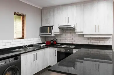 a kitchen with white cabinets and a washer and sink at Greenwaywoods Unit 11 in White River