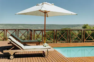 a white umbrella sitting on a deck next to a pool at Dinkweng Safari Lodge in The Waterberg Biosphere