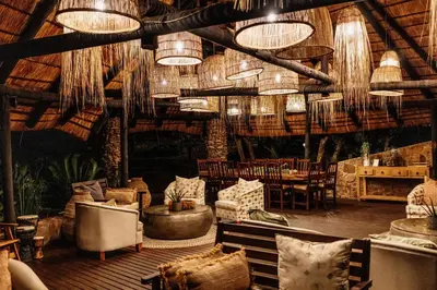 a living room with chairs and tables and chandeliers at Dinkweng Safari Lodge in The Waterberg Biosphere