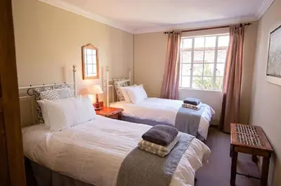 a hotel room with two beds and a window at Bluebell Cottage in Dullstroom
