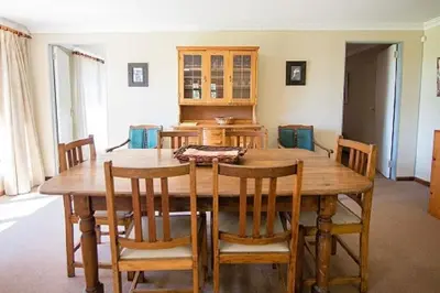 a dining room with a wooden table and chairs at Bluebell Cottage in Dullstroom