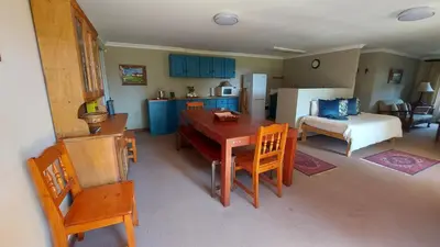 a kitchen and living room with a table and chairs at Bluebell Cottage in Dullstroom