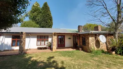 a white house with a clock in the yard at Bluebell Cottage in Dullstroom