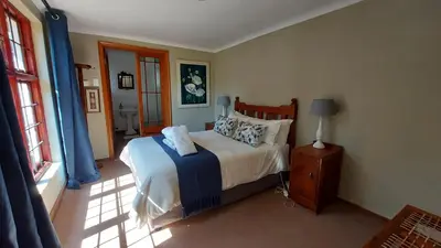 a bedroom with a bed with blue curtains and a window at Bluebell Cottage in Dullstroom
