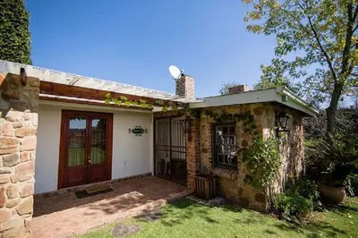a brick house with a red door in a yard at Bluebell Cottage in Dullstroom