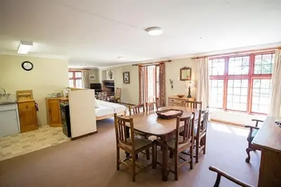 a kitchen and living room with a table and chairs at Bluebell Cottage in Dullstroom