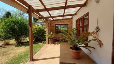 a patio with a wooden pergola and a bench at Bluebell Barn in Dullstroom