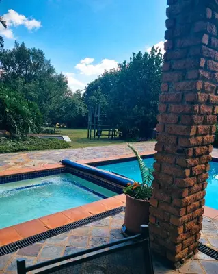a swimming pool with a chair next to a brick pillar at Cycad Place Midrand Guesthouse and B&B in Midrand