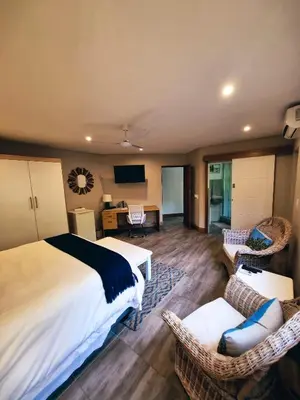 a bedroom with a bed and chairs and a desk at Cycad Place Midrand Guesthouse and B&B in Midrand