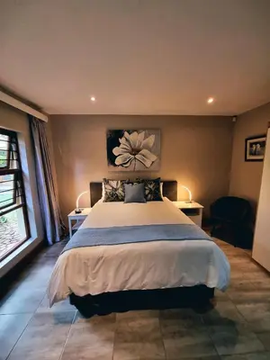 a bedroom with a large bed with two tables and two lamps at Cycad Place Midrand Guesthouse and B&B in Midrand