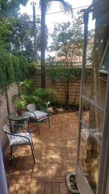 a patio with two chairs and a table and a glass door at Love Joy Peace Cottage in Pretoria