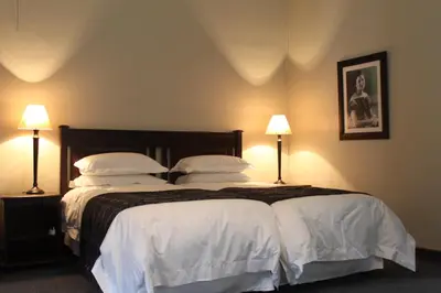 a bedroom with a large bed with white sheets and pillows at Morgenzon Estate in Pretoria