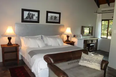 a bedroom with a bed and a chair and two lamps at Morgenzon Estate in Pretoria