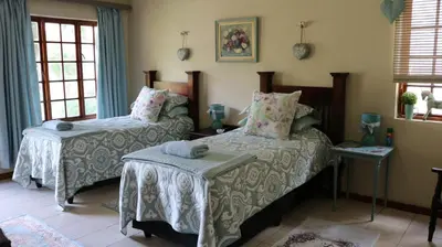 a bedroom with two beds and a table at Mia's in Tzaneen