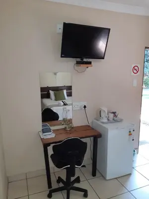 a desk with a chair and a television on a wall at Lepha Guest House in Onverwacht