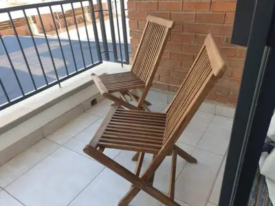 two wooden chairs sitting on a balcony looking out at the water at The Blyde Lagoon, Pretoria in Pretoria
