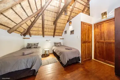 two beds in a room with wooden ceilings at Niani villa in Hoedspruit