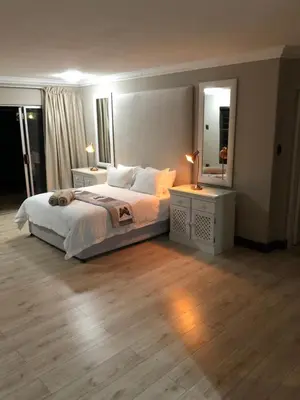 a bedroom with a bed with two night stands and a mirror at Annies Place Self Catering in Kempton Park