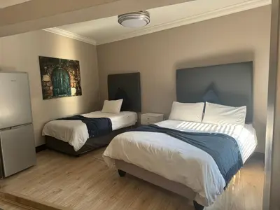 a bedroom with two beds and a refrigerator at Annies Place Self Catering in Kempton Park