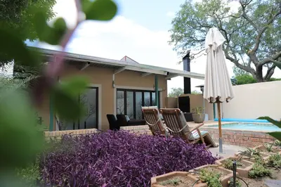 a patio with an umbrella and chairs and a pool at Memories Made Cottage in Kampersrus AH