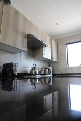 a kitchen with wooden cabinets and a tea kettle at Memories Made Cottage in Kampersrus AH