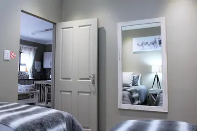 a bedroom with a mirror next to a bed at @Home in the East in Pretoria