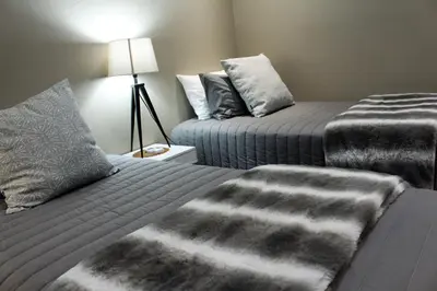 a bedroom with two beds with grey blankets and a lamp at @Home in the East in Pretoria