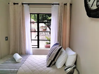 a bedroom with a bed with a window and a clock at @Home in the East in Pretoria