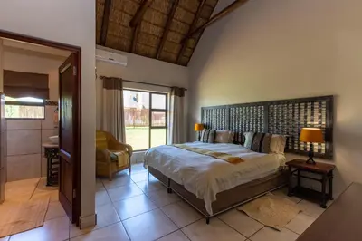 a bedroom with a large bed and a bathroom at Zebula - HT1 - 5 Bedroom Holiday Home in Mabula