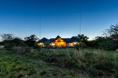 a house lit up at night in a field at Zebula - HT1 - 5 Bedroom Holiday Home in Mabula