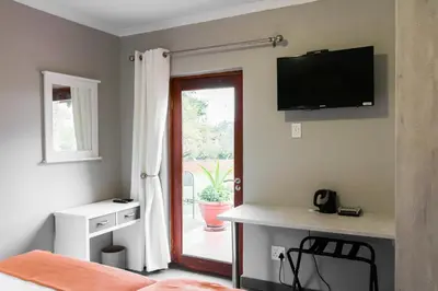 a bedroom with a bed and a television on the wall at Unit 12, Greenway Woods, White River in Die Winkler