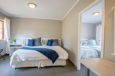 a bedroom with two beds and a mirror at Unit 12, Greenway Woods, White River in Die Winkler