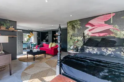 a bedroom with a bed and a red chair in a room at The Hideaway in Benoni