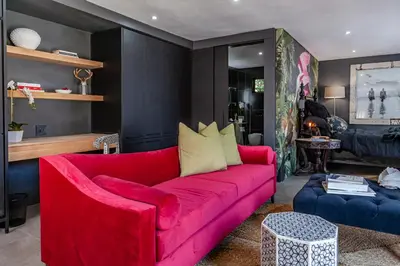 a living room with a red couch and a blue chair at The Hideaway in Benoni