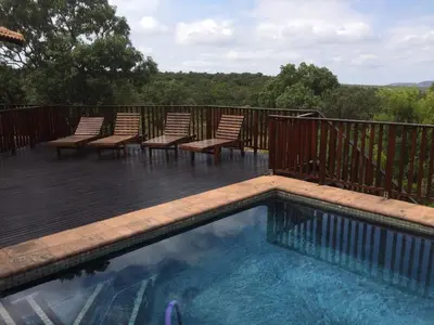 a swimming pool with chairs on a deck at Elements golf reserve in Bela-Bela