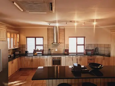 a large kitchen with wooden cabinets and a black counter top at Elements golf reserve in Bela-Bela