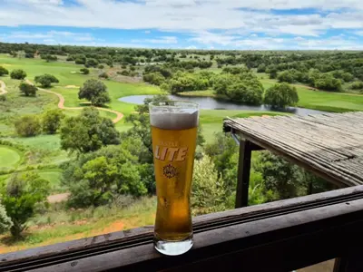 a glass of beer sitting on a balcony with a view at Elements golf reserve in Bela-Bela