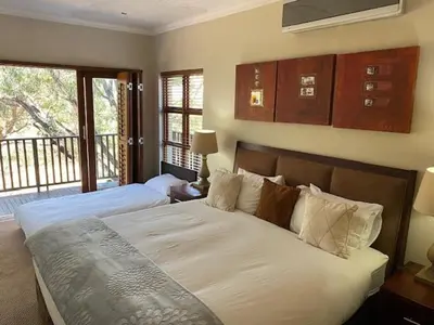 a bedroom with two beds and a balcony at Elements golf reserve in Bela-Bela