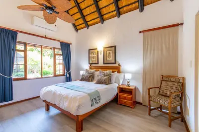 a bedroom with a bed and a fan and a chair at Kruger Park Lodge Unit No. 239 in Hazyview