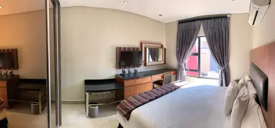 a hotel room with a bed and a desk and a television at 66 Dorp Street Apartment in Polokwane