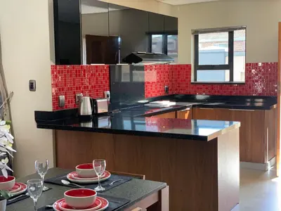 a kitchen with black counter tops and red tiles at 66 Dorp Street Apartment in Polokwane