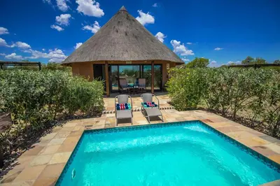 a swimming pool with two chairs and a gazebo at Golden Impalas Bush Resort in Hammanskraal