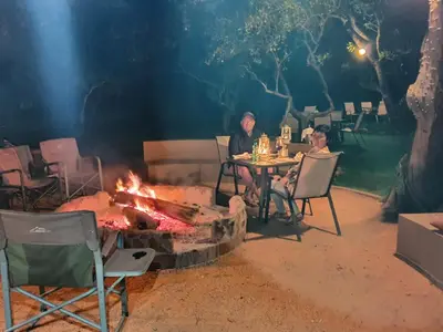 two people sitting at a table around a fire pit at Golden Impalas Bush Resort in Hammanskraal