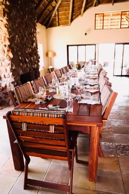 a long wooden table with chairs and glasses on it at Golden Impalas Bush Resort in Hammanskraal