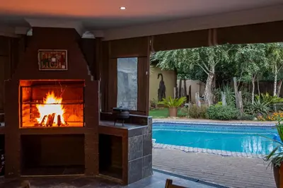 a fireplace in a living room next to a swimming pool at Blyde Africa- Cottage in Benoni
